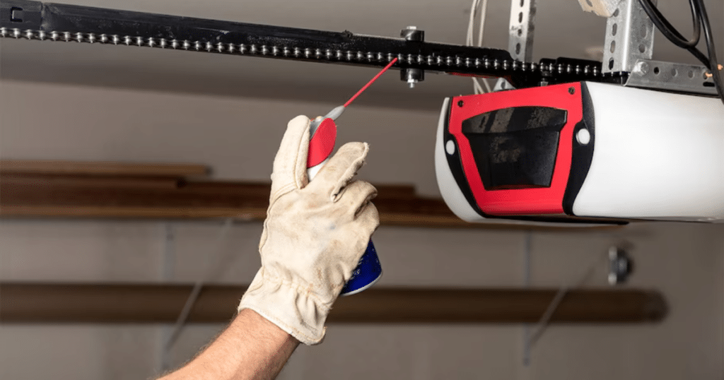 Person lubricating a garage door chain with a spray can.